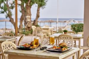 a table with two plates of food and two glasses of beer at Blue Sea Beach Resort in Faliraki
