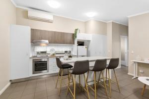a kitchen with white cabinets and a table with chairs at Umina Myrtle Bungalow Sleeping 4 Guests in Blackwall