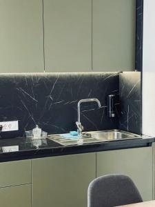 a kitchen counter with a sink and a chair at Zen Apartments Pejë in Peje
