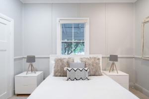 a white bedroom with a white bed and two lamps at Janie s Cottage Secluded Wine Country Home in Broke
