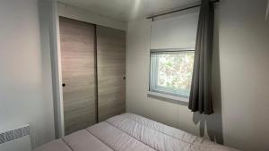 a bedroom with a bed and a window at Petit Cocon au Cap Ferret Camping les Embruns in Lège-Cap-Ferret