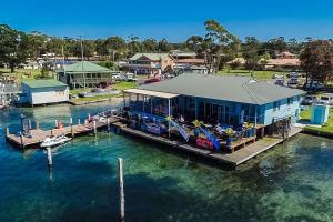 a house on a dock in the water at Meroo Meadow Magic Charming Cottage Retreat in Meroo