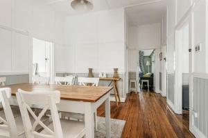 a dining room with a wooden table and white chairs at Meroo Meadow Magic Charming Cottage Retreat in Meroo