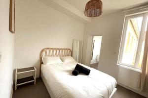 a bedroom with a white bed with a black bag on it at Charmant appartement Près de la Gare in Saint-Quentin