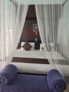 una camera da letto con letto con tende bianche e cuscini viola di Private villa with swimming pool a Kuta