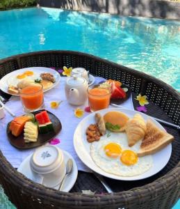 un tavolo per la colazione con cibi e bevande per la colazione e una piscina di Private villa with swimming pool a Kuta