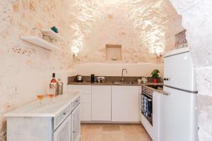 a kitchen with white cabinets and a white refrigerator at Borgo dei trulli Fanelli in Castellana Grotte