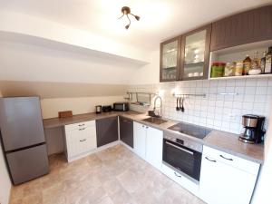 Una cocina con gabinetes blancos y un refrigerador de acero inoxidable. en Aparte 3-Zi-Wohnung im Oberallgäu direkt am Berg!, en Immenstadt im Allgäu