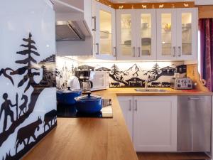 Una cocina con gabinetes blancos y animales en la pared. en Apartment Le Bristol A52 by Interhome, en Villars-sur-Ollon