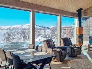 a dining room with a table and chairs and snow covered mountains at Holiday Home Loimu by Interhome in Kilpisjärvi
