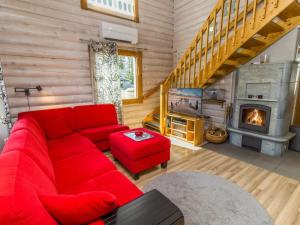 ein Wohnzimmer mit einem roten Sofa und einem Kamin in der Unterkunft Holiday Home Rukanlyhty by Interhome in Rukatunturi  + 14 Fotos