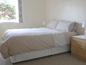 Una cama blanca en un dormitorio con ventana. en Holiday Home Glamaig by Interhome, en Portree
