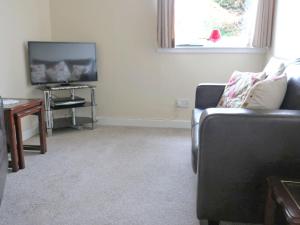 Una sala de estar con un sofá y un televisor. en Holiday Home Glamaig by Interhome, en Portree