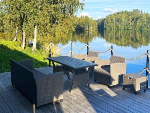 une terrasse en bois avec une table et des chaises à côté d'un lac dans l'établissement Holiday Home Brofeldt by Interhome, à Tohmajärvi