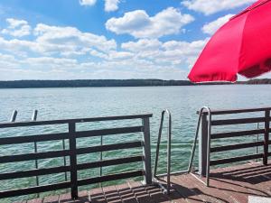 a red umbrella sitting on a dock next to the water at Chalet Bootshaus auf dem See by Interhome in Lindow +7 photos
