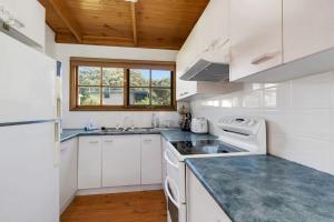 una cucina con elettrodomestici bianchi e soffitto in legno di Muwarra Cottage Malua Bay a Malua Bay
