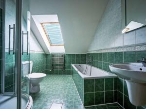 a green tiled bathroom with a sink and a toilet at Apartment Harrachov 613-2 by Interhome in Harrachov