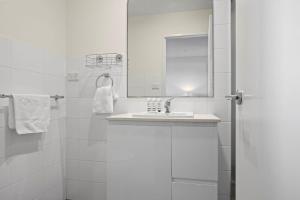 a white bathroom with a sink and a mirror at The Perch Gorgeous 3 Bedroom Penthouse in Wollongong