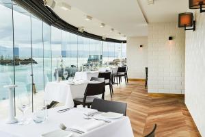 a restaurant with white tables and chairs and large windows at The Perch Gorgeous 3 Bedroom Penthouse in Wollongong