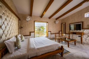 a bedroom with a bed and a table and a television at Hukamgarh - A Luxury Boutique Resort in Nawalgarh