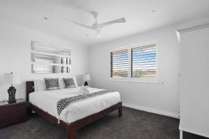 a white bedroom with a bed and a ceiling fan at Dream View Steps from the Beach in Sydney