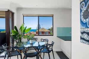 a dining room with a table and chairs and a window at Dream View Steps from the Beach in Sydney