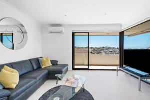 a living room with a couch and a glass table at Dream View Steps from the Beach in Sydney