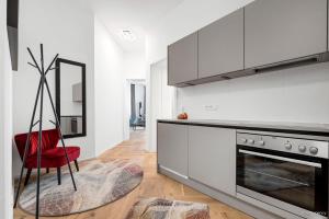 a kitchen with white cabinets and a red chair at easy-flat Rokitanskygasse - Apartments near Tram 43 to City Center in Vienna
