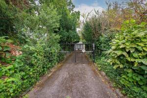 a gate in the middle of a dirt road at 5 Bed Home with Private Parking - 25 Mins To Central London in Cockfosters