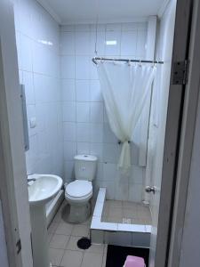 a white bathroom with a toilet and a sink at Hostal Julpaz Orella in Iquique