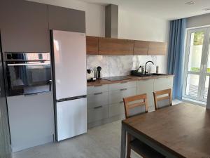 una cucina con frigorifero bianco e tavolo in legno di Apartament Mazurski a Nidzica Altre 8 foto