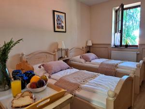 two beds in a room with a table with a bowl of fruit at Leimen Centrum in Mány