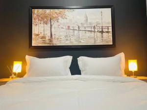 a bedroom with a white bed with a painting on the wall at Apparent Self Catering in Boschrand