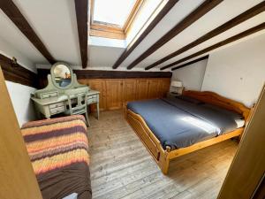 a bedroom with a bed and a desk and a mirror at Brici's House 69 - Mountain Apartment Tonale in Passo del Tonale