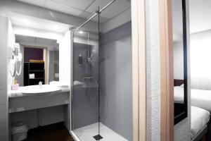 une salle de bain avec douche et lavabo dans l'établissement Brit Hotel Montpellier Parc Expo, à Pérols