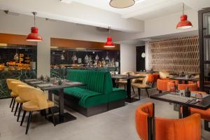 a restaurant with a green couch and tables and chairs at Anise Aluma Athens, Tapestry Collection by Hilton in Athens