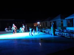 un gruppo di persone che camminano su un palco di notte di Dune Delite Jaisalmer a Sām