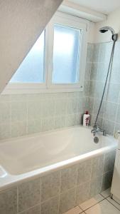 La salle de bains est pourvue d'une baignoire blanche et d'une fenêtre. dans l'établissement La Couregant House vue mer, à Ploemeur 28 autres photos