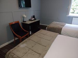 a hotel room with a bed and a chair and a desk at Kings Park Hotel in Glasgow
