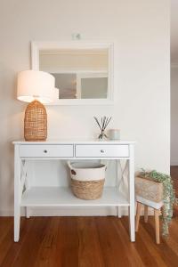 a white console table with a mirror and a basket at Ocean Views Walk to Malua Beach EV & Pet Friendly in Malua Bay
