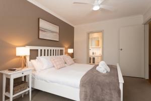 a bedroom with a large white bed with a night stand at Ocean Views Walk to Malua Beach EV & Pet Friendly in Malua Bay