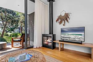 a living room with a fireplace and a television at Privately Managed Villa 12 Bangalay Luxury Villas in Shoalhaven Heads