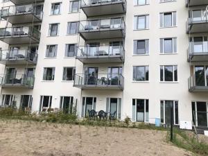 een wit gebouw met stoelen en tafels ervoor bij Beach apartment Prora Captain in Prora +9 foto's