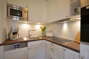 a kitchen with white cabinets and a sink and a microwave at Bornholm Whg2 in Nieblum