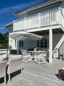 a patio with wicker chairs and an umbrella at Drømmested for idylliske dager in Skjoldastraumen