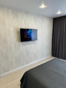 a bedroom with a bed and a tv on the wall at Люкс Апартаменты Gray Pearl на Подолье in Vinnytsya