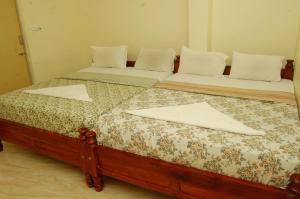 two beds sitting next to each other in a room at Sankara Residency in Kanchipuram