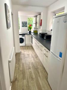 a kitchen with white appliances and a wooden floor at 4B4B Entire House Sleeps 11 Driveway Parking near Coventry University and City Centre in Coventry