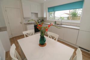 a white kitchen with a vase with flowers on a table at Bod A Quinte in St Ives