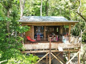 a cabin in the woods with chairs and a table at cabane entre les arbres in Deshaies